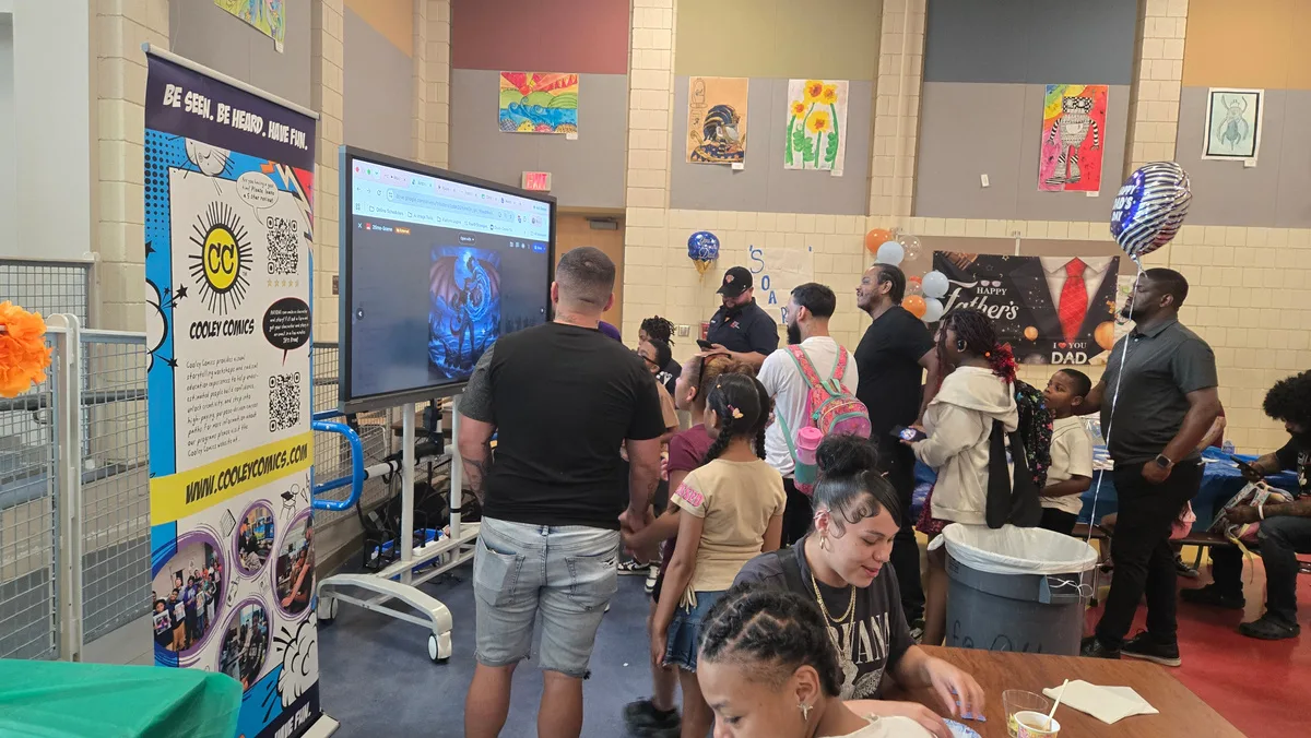 Families gathered around tables and a screen at the School 33 Dads and Donuts event